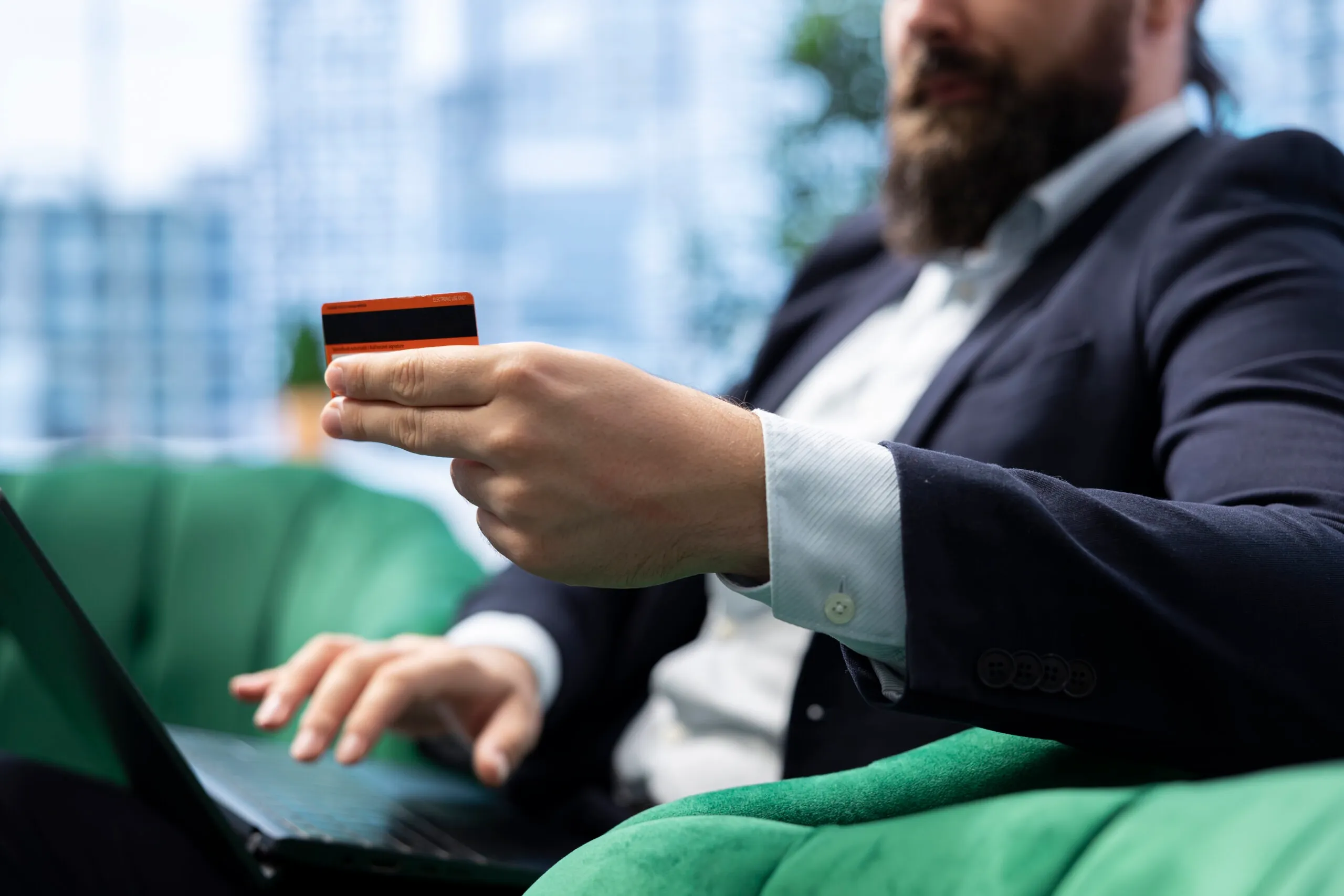A focused businessman looking at his credit card, illustrating how he uses the best business credit card for small business to manage company capital