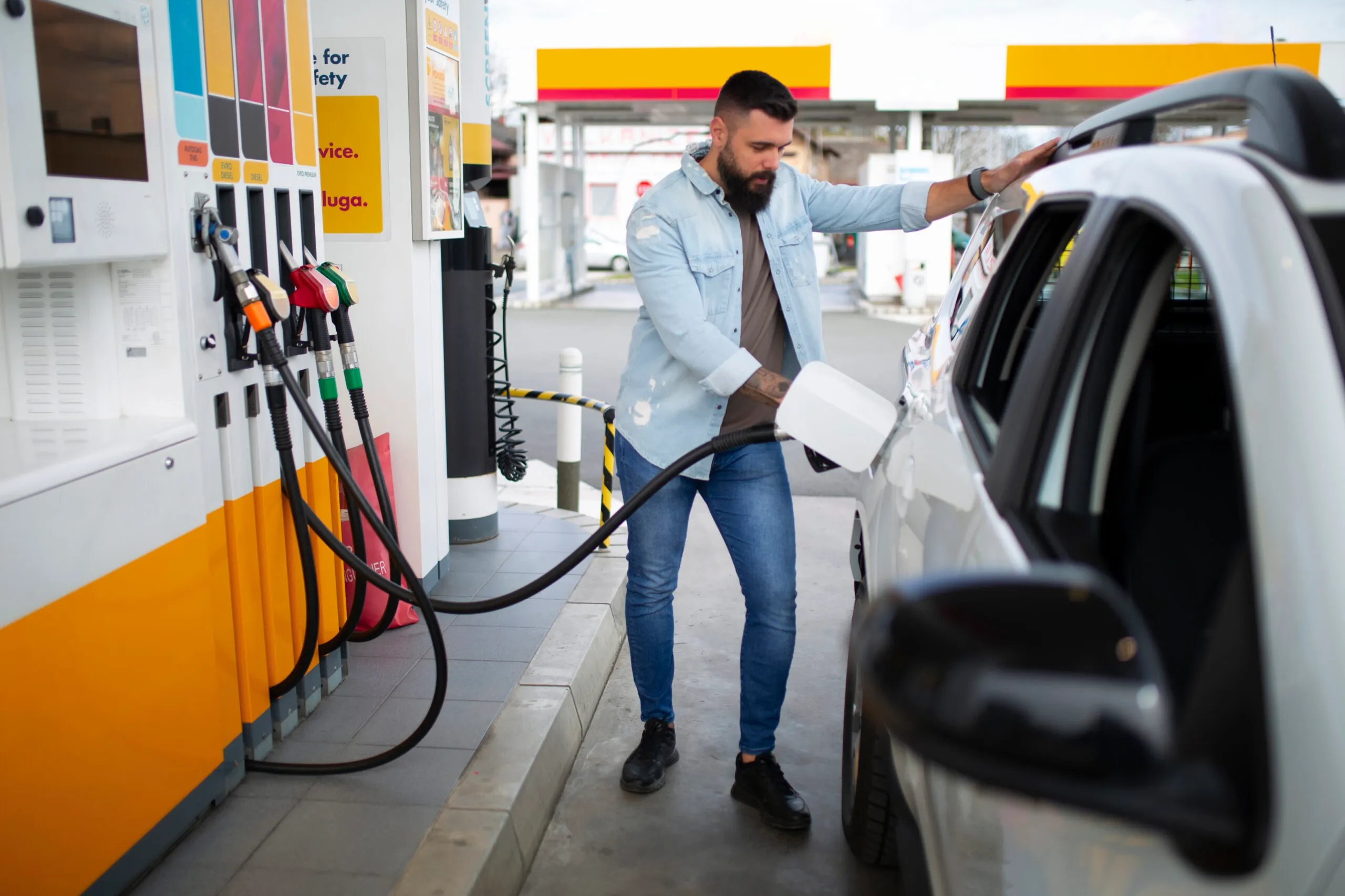 A man fueling his car at a petrol pump, reflecting the consumer impact of the trends affecting fuel price today February 17