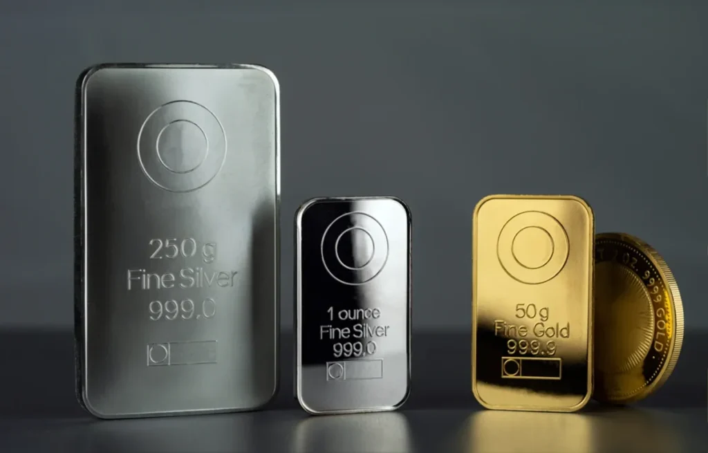 Assorted gold and silver biscuits and coins arranged together, representing the recent gold and silver price fall today.